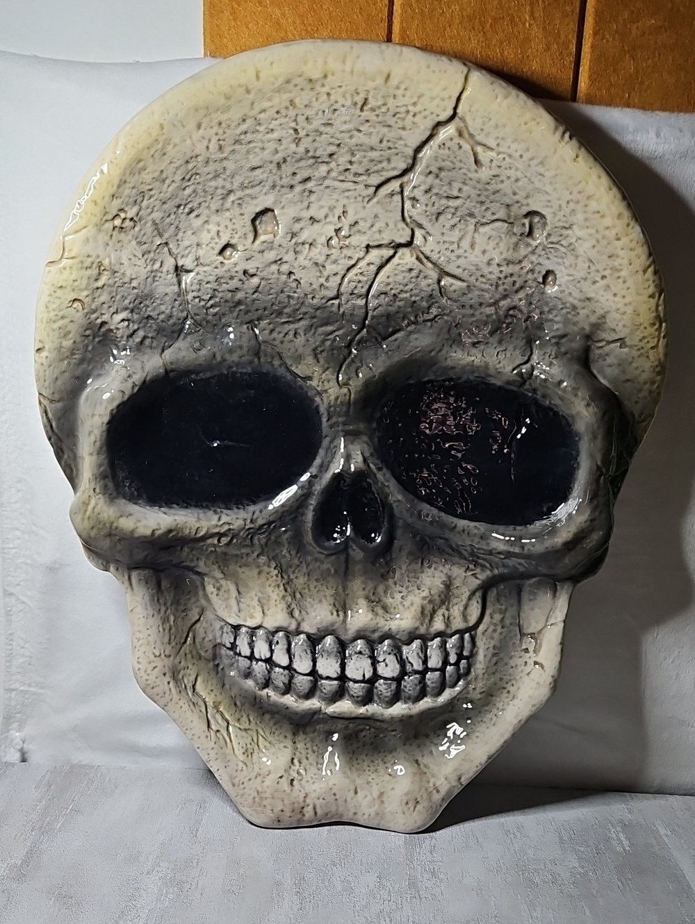 ceramic skull serving platter features a distressed, cracked gray finish